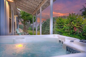 Un jacuzzi bajo una pérgola con vistas a un jardín y al atardecer.