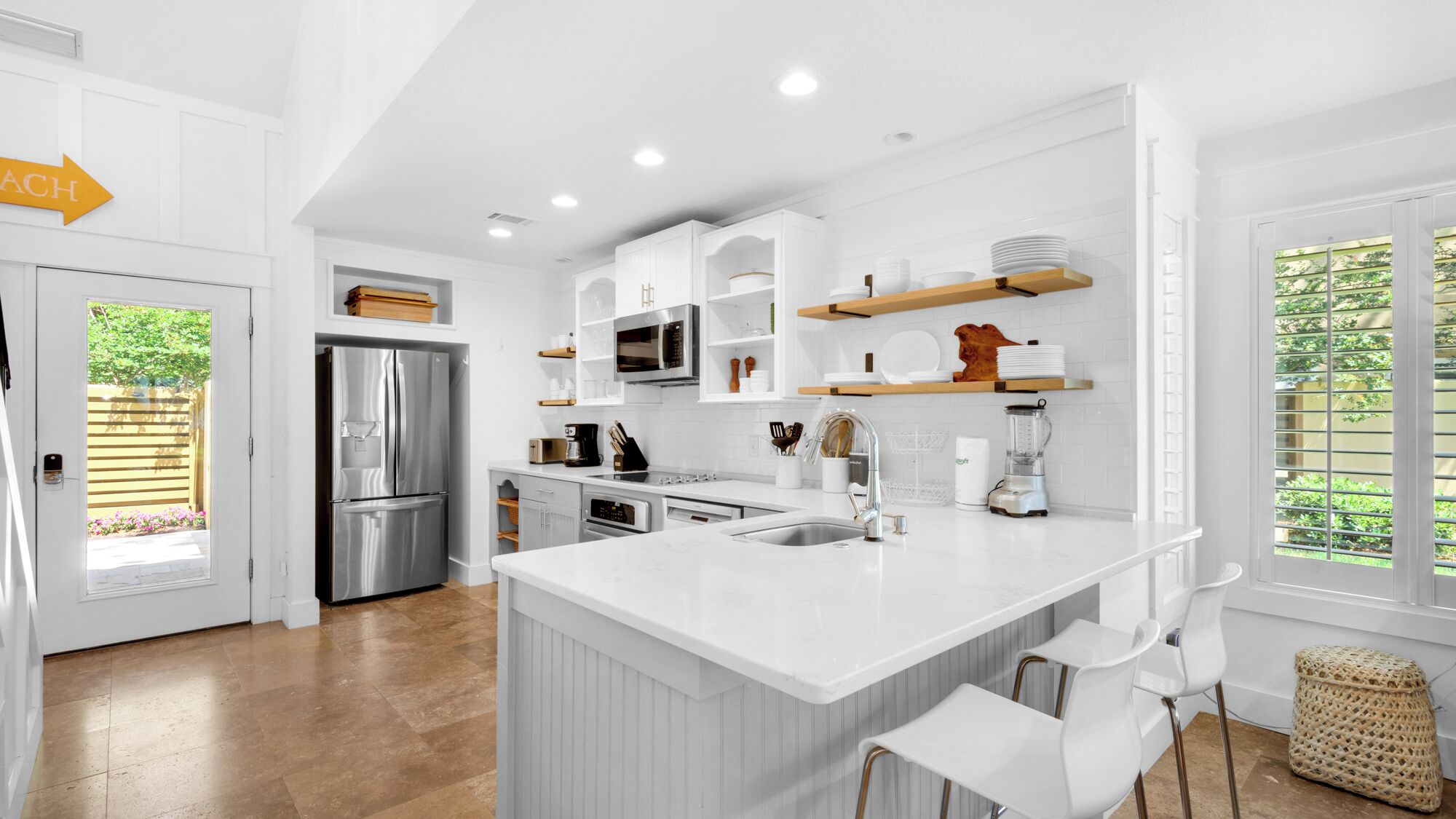 A modern kitchen with white cabinetry, stainless steel appliances, and a large island with bar stools.