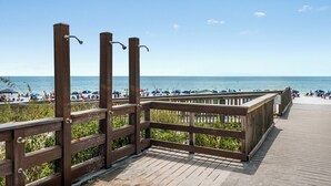 Une promenade en bois offrant une vue sur la plage et l’océan.