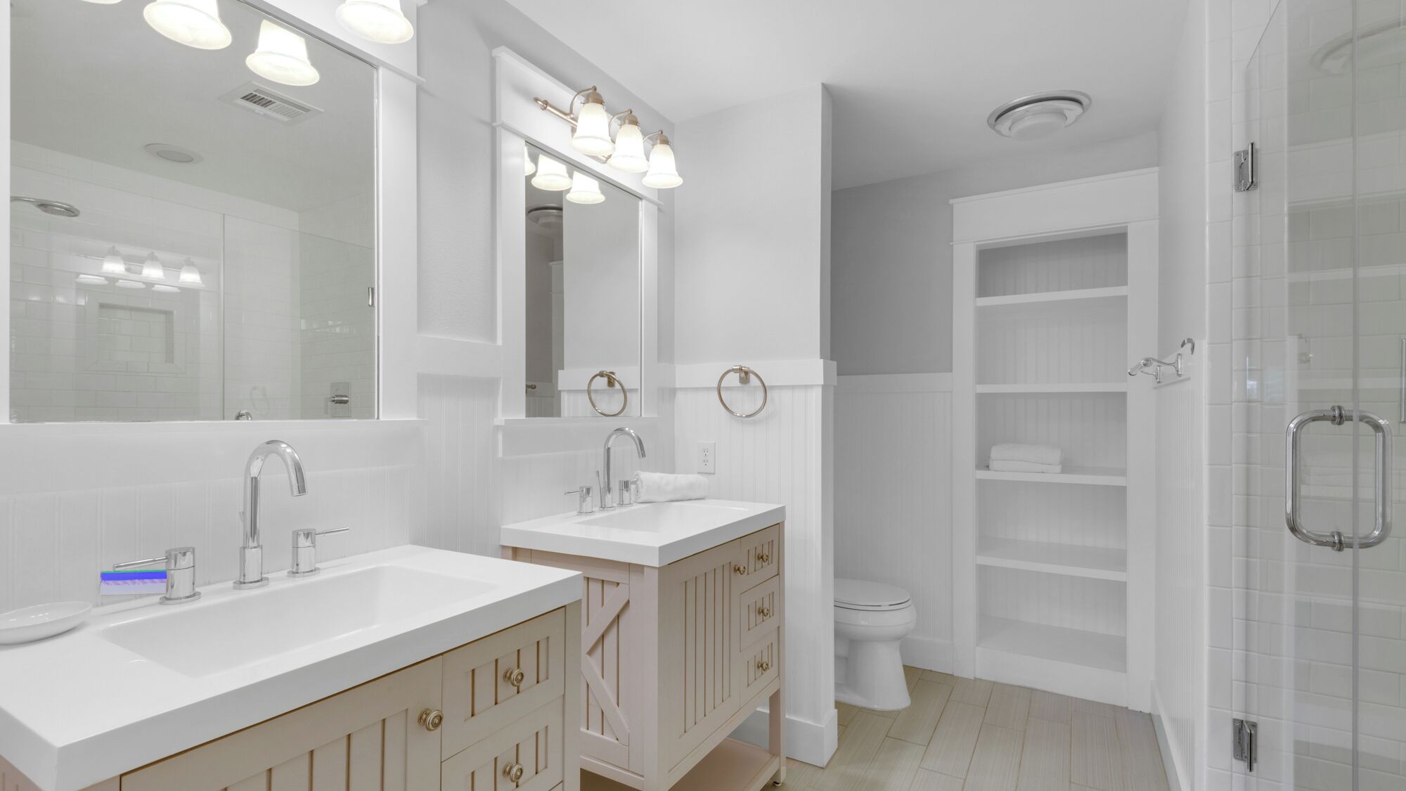 Een moderne badkamer met twee wastafels, een grote spiegel en een douchecabine met glazen wanden.