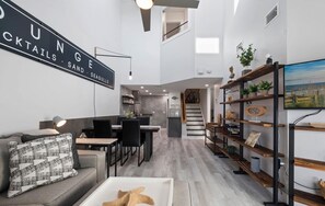Ein modernes Wohnzimmer mit Essbereich, einer Treppe und einer Küche.