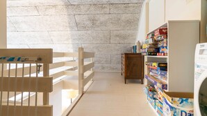 A room with a white crib, a bookshelf with board games, and a washing machine. - Apartment with balcony in Veere | Buiten de Veste 36 (Veere)