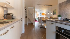 A modern kitchen with a dining area, wooden flooring, and a staircase leading to a living space. - Apartment with balcony in Veere | Buiten de Veste 36 (Veere)