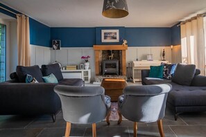 A living room with a fireplace, two sofas, a coffee table, and a lamp. - Chambre D'hôte "La Roche Au Cerfs", La Haye D'armor (Le Mené)