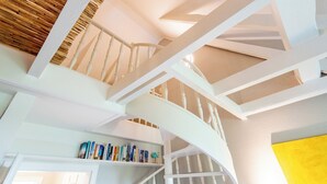 Una scala bianca con soffitto in legno e parete gialla.