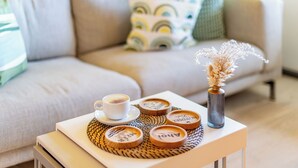 Un soggiorno accogliente con un divano, un tavolino, un vaso con fiori secchi e una tazza di caffè.
