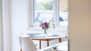 Een moderne keuken met een eettafel, stoelen en een bloevas op de vensterbank.