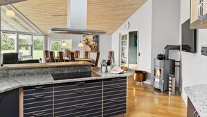 Eine moderne Küche mit einer zentralen Kochinsel, Holzboden und einem eingebauten Holzofen.