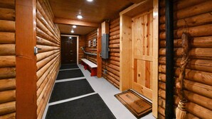 A log cabin interior with a wooden hallway, benches, a door, and a welcome mat. - Cabin of Hygge: 19 Miles to Yellowstone (Island Park)