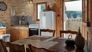 Una cocina rústica con una mesa, sillas, estufa y refrigerador.