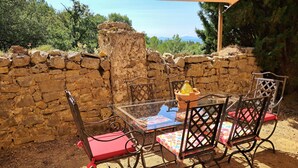 Un muro de piedra, una mesa con sillas y vistas al paisaje.