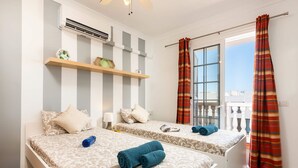 A hotel room with two beds, striped wall decor, a ceiling fan, and a window with curtains. - Villa Naranja with private heated pool, sea views (Callao Salvaje)