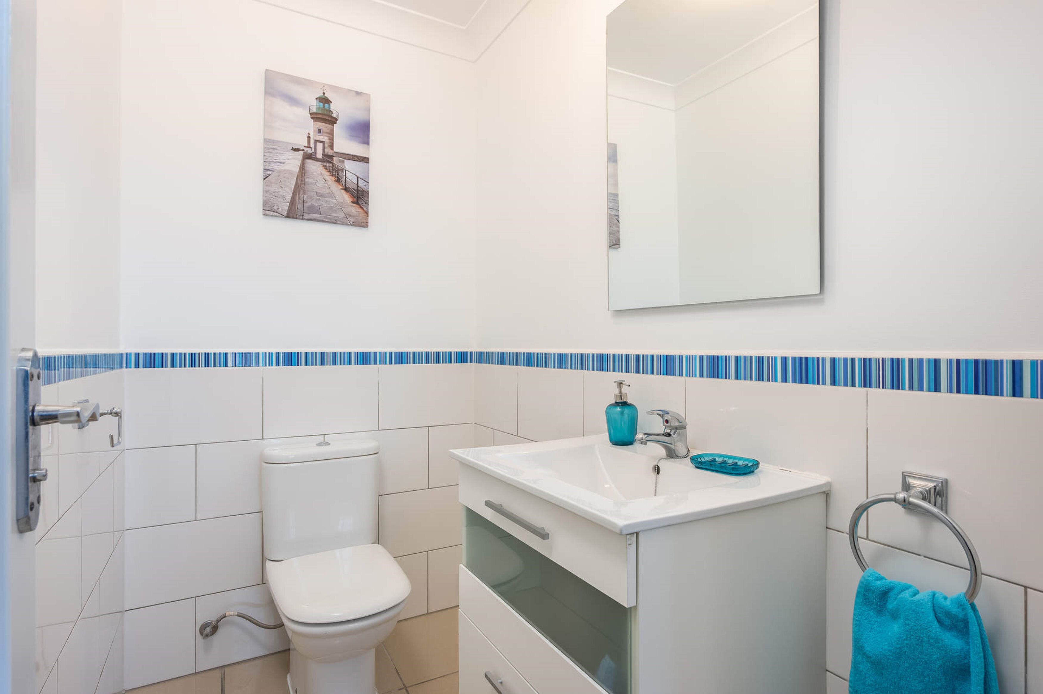 Een badkamer met toilet, wastafel en spiegel.