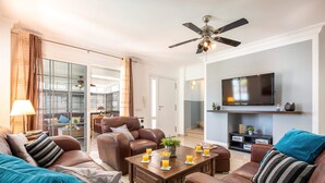 A modern living room with leather sofas, a coffee table with drinks, a ceiling fan, and a TV mounted on the wall. - Villa Naranja with private heated pool, sea views (Callao Salvaje)