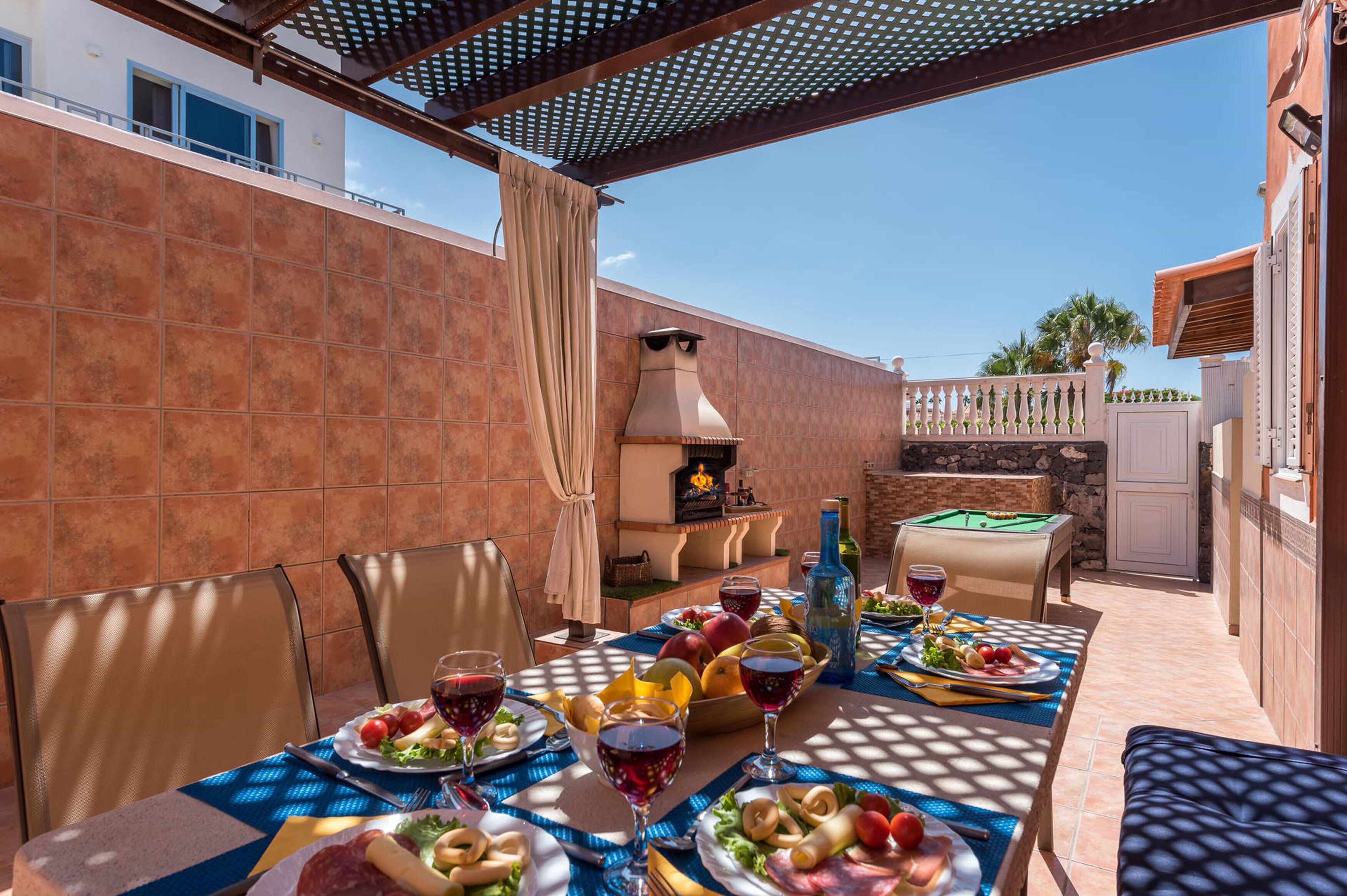 Ein Essbereich im Freien mit Tisch, Grill und Billardtisch.