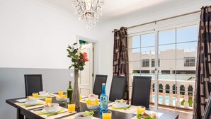 A dining area with a long table set for breakfast, including bowls of food, glasses of orange juice, and a bottle of water. - Villa Naranja with private heated pool, sea views (Callao Salvaje)