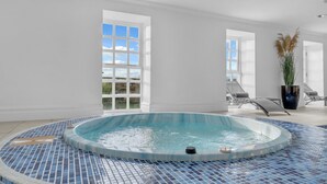 A modern indoor swimming pool with a tiled floor, large windows, and lounge chairs. - Hunter Oak Retreat, Indoor heated pool, Sauna, Hot Tub Sleeps 30 (Burnley)
