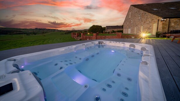A hot tub on a wooden deck with a sunset in the background. - Hunter Oak Retreat, Indoor heated pool, Sauna, Hot Tub Sleeps 30 (Burnley)