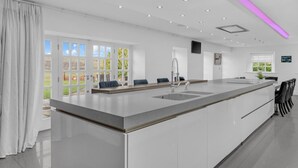 A modern kitchen with a large island, built-in appliances, and a view of the outdoors. - Hunter Oak Retreat, Indoor heated pool, Sauna, Hot Tub Sleeps 30 (Burnley)