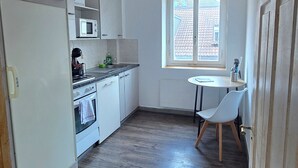 A kitchen with a microwave, stove, and sink. There is a window with a view of the outside. - Charming 2-bedroom apartment in vibrant Zürich with WiFi (Zürich)