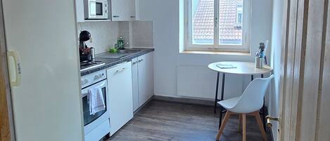 A kitchen with a microwave, stove, and sink. There is a window with a view of the outside.