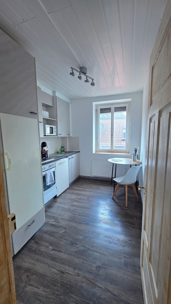 A kitchen with a microwave, stove, and sink. There is a window with a view of the outside.
