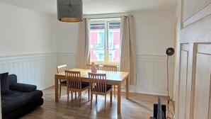 A room with a dining table, chairs, a sofa, a TV, and a window with curtains. - Charming 2-bedroom apartment in vibrant Zürich with WiFi (Zürich)