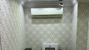 A reception desk with a logo, patterned wallpaper, and a ceiling-mounted air conditioner. - Sama Samah Hotel (Makkah)
