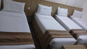 A hotel room with four single beds arranged in a row, each with white bedding and a wooden headboard. - Sama Samah Hotel (Makkah)