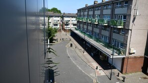 Ein mehrstöckiges Wohngebäude mit Balkonen, einem Fußweg und einer Straße davor.