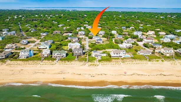 Una vista aerea di una zona residenziale costiera con case, una spiaggia e un tratto d'acqua.
