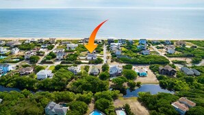 Vista aerea di una zona residenziale costiera con case, vegetazione e una distesa d'acqua.