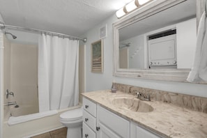 A bathroom with a bathtub, toilet, sink, and a large mirror.