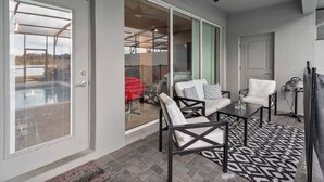 A covered patio area with a ceiling fan, outdoor seating with cushions, and a patterned rug. - Townhouse w/ pool & resort water park (Davenport)