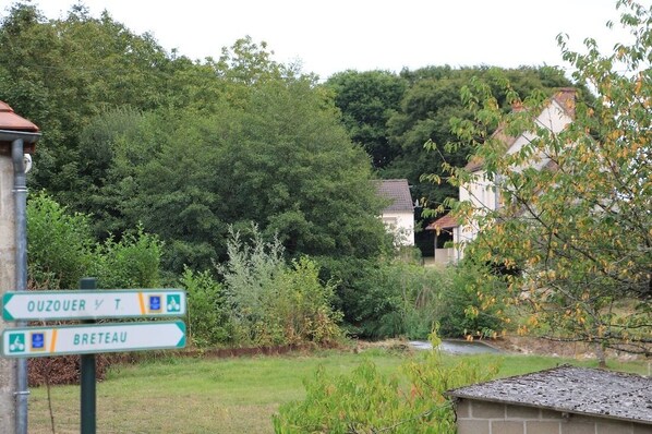 Un panneau indicateur indiquant les directions vers Ouzouer et Breteau, entouré de verdure et bordé d’un quartier résidentiel.
