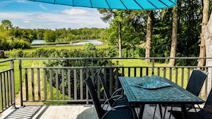 A balcony with a table and chairs, overlooking a golf course.