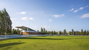Un bâtiment moderne doté d’un toit plat et de grandes fenêtres, entouré d’une pelouse bien entretenue et d’une clôture blanche.