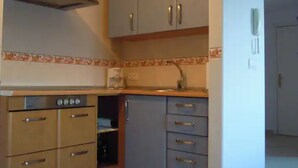 A compact kitchen with a built-in oven, a stainless steel range hood, and light-colored cabinets. - Apartamento Para 4 Personas en Playa Jardín Boiro, Puerto de Escarabote (Boiro)