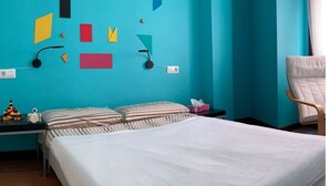 A room with teal walls, a bed with striped bedding, a chair, and geometric wall art. - Apartamento Para 4 Personas en Playa Jardín Boiro, Puerto de Escarabote (Boiro)