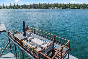 Eine Terrasse mit Sitzgelegenheiten, einer Brüstung und Blick auf einen See mit bewaldeter Uferzone.