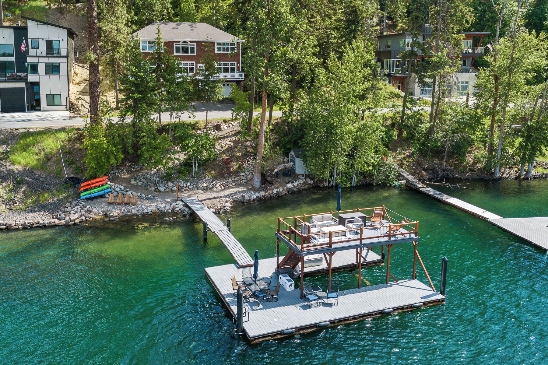 A dock with a boat, surrounded by trees and a building in the background.