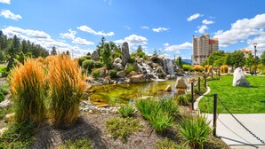 Un jardín ajardinado con un estanque, rocas y un sendero.