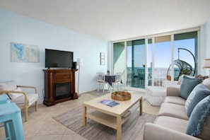 Relax in this stylish living room with a flat-screen TV, cozy fireplace, and sliding glass door leading to a balcony with a sea view.