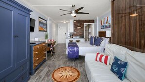 A compact living space with a dining area, kitchenette, and a sofa with decorative pillows.