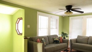 Ein Wohnzimmer mit grüner Wand, Deckenventilator, Sofa und Couchtisch.