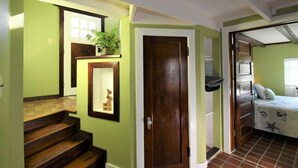 Eine Treppe führt zu einem Schlafzimmer mit einem Bett, einem Nachttisch und einer Zimmerpflanze.