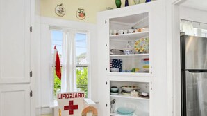 A kitchen with white cabinetry, a stainless steel refrigerator, and a window with a 'LIFEGUARD' sign. - Welcome to "The Sunrise Inn!" (Galveston)