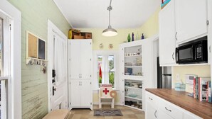 A kitchen with white cabinets, a microwave, and a small island with a wooden countertop. - Welcome to "The Sunrise Inn!" (Galveston)