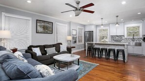 A modern living room with a grey sofa, a coffee table, and a ceiling fan.