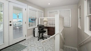 A narrow hallway with a desk and chair, a radiator, and a white railing.